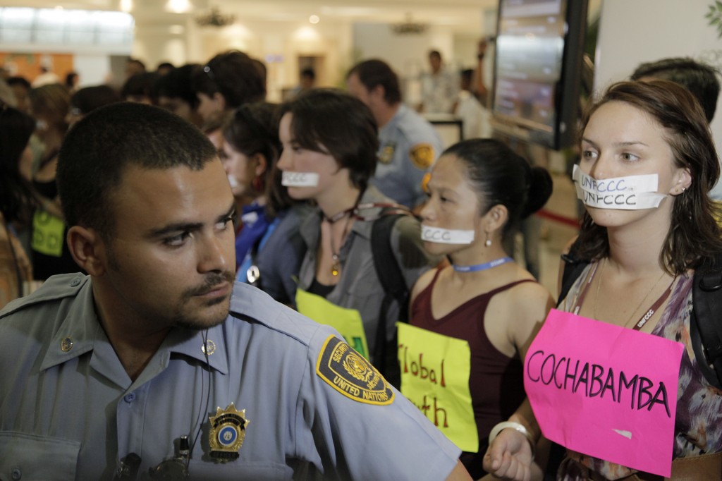 Protesters getting kicked out of the UN Climate Conference, 16TH SESSION OF THE CONFERENCE OF THE PARTIES (COP 16), . Their taped mouths represent their voices being silenced. Photo © Tristan Bayer www.earthnative.com. From the documentary film Revolution